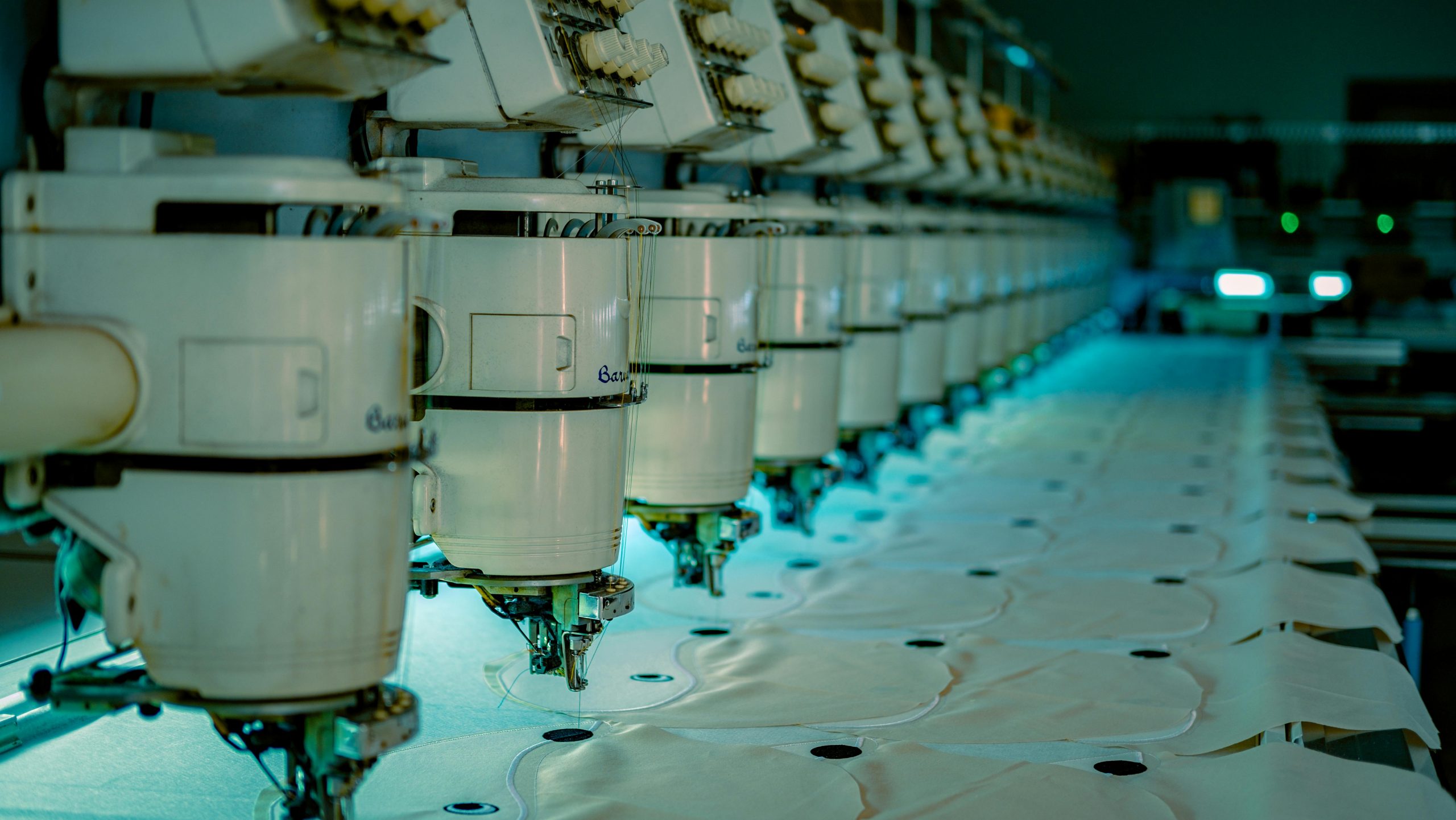 智慧製造工廠內部照片,顯示整排自動化縫紉或刺繡機台正在運作。